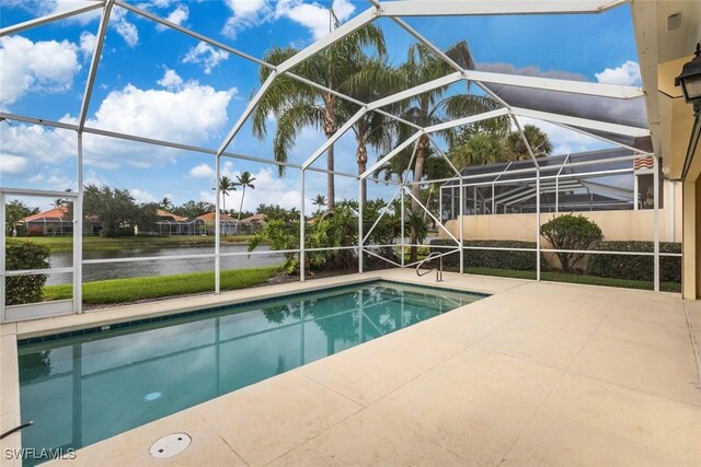 outdoor pool featuring a water view, a patio area, and glass enclosure