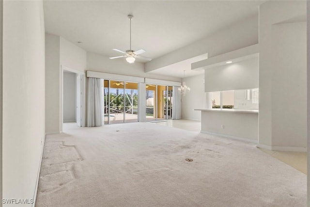 unfurnished living room featuring light carpet, ceiling fan, a chandelier, and baseboards