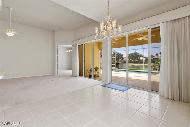 empty room with a ceiling fan, carpet floors, tile patterned flooring, and a chandelier