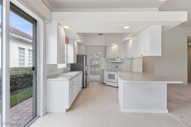 kitchen with white appliances, light countertops, a peninsula, light tile patterned floors, and recessed lighting