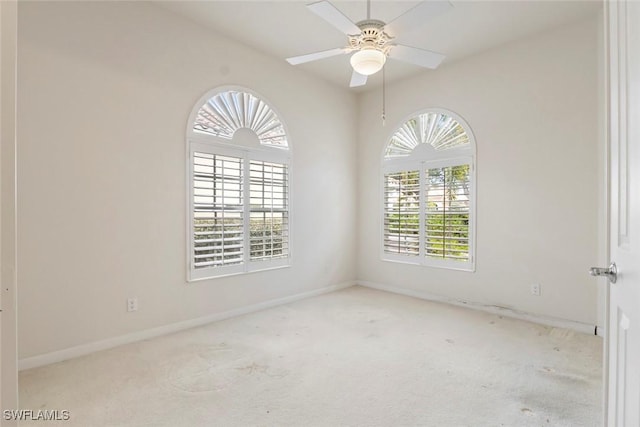 carpeted empty room featuring baseboards and a ceiling fan