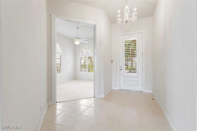 doorway to outside with a chandelier, light tile patterned floors, baseboards, and a ceiling fan