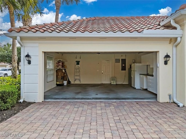 garage with electric panel, driveway, and freestanding refrigerator