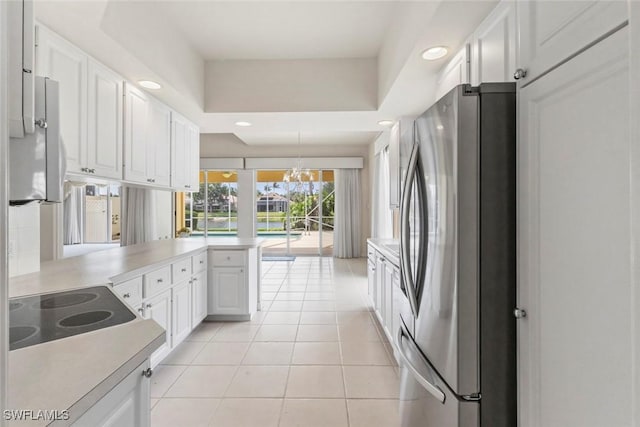 kitchen featuring freestanding refrigerator, a peninsula, white cabinetry, light tile patterned floors, and light countertops