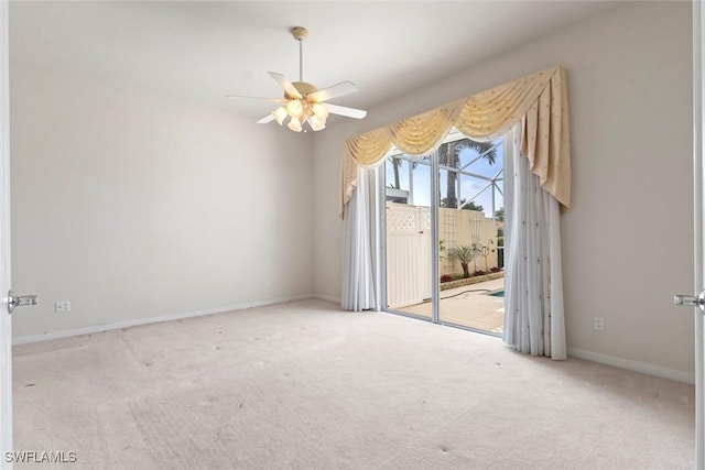carpeted spare room with a ceiling fan and baseboards