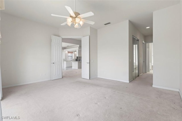 empty room featuring baseboards, light colored carpet, and a ceiling fan