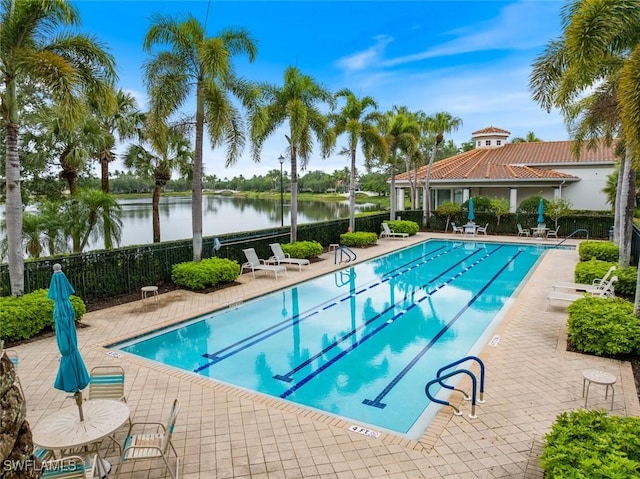 community pool featuring fence, a patio area, and a water view