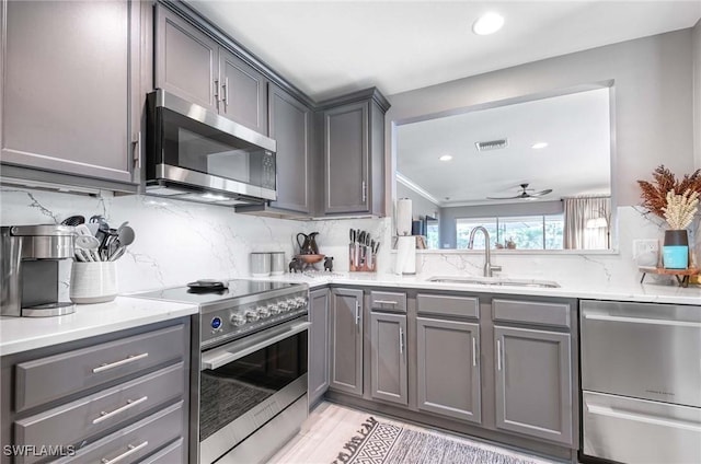 8661 Querce Ct, Naples, FL 34114 - kitchen with stainless steel appliances, gray cabinets, a sink, decorative backsplash, and ceiling fan