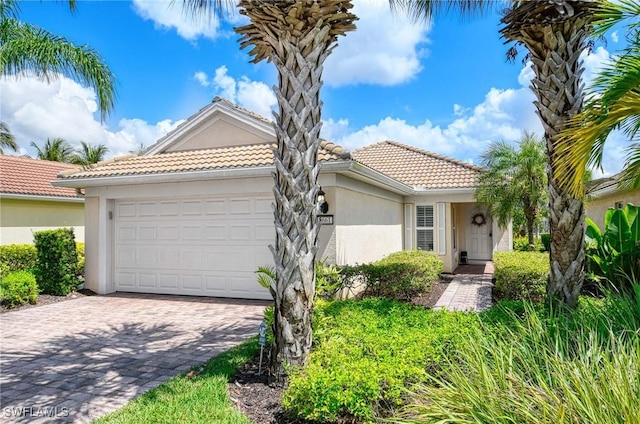 8661 Querce Ct, Naples, FL 34114 - mediterranean / spanish home with stucco siding, an attached garage, a tiled roof, and decorative driveway