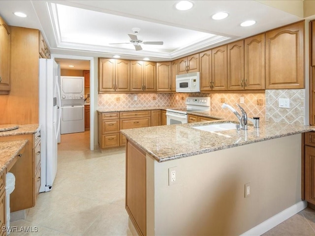 840 S Collier Blvd Unit 706, Marco Island, FL 34145 - kitchen with white appliances, a sink, a peninsula, stacked washer / drying machine, and light stone countertops