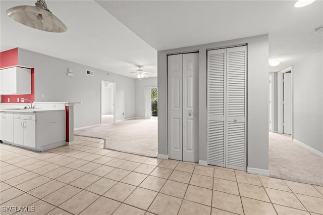 27075 Matheson Ave Unit 105, Bonita Springs, FL 34135 - kitchen with light colored carpet, a ceiling fan, light tile patterned floors, and white cabinets