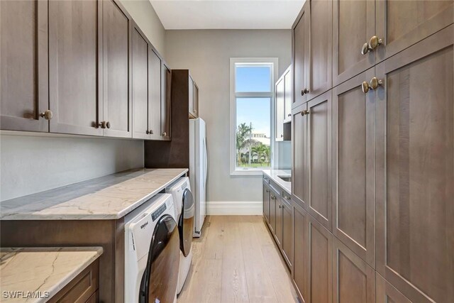 26906 Mclaughlin Blvd, Bonita Springs, FL 34134 - clothes washing area with independent washer and dryer, baseboards, light wood finished floors, and cabinet space