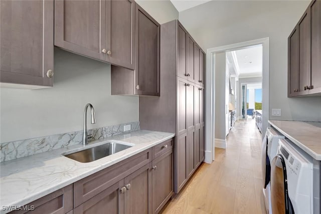 26906 Mclaughlin Blvd, Bonita Springs, FL 34134 - kitchen featuring a sink, washer and clothes dryer, light wood-style flooring, and light stone counters