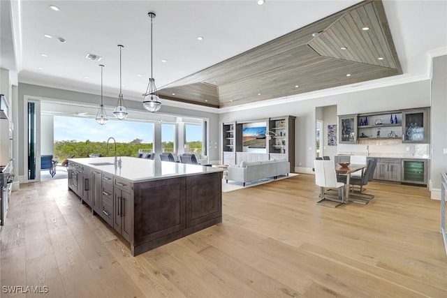 26906 Mclaughlin Blvd, Bonita Springs, FL 34134 - kitchen with wine cooler, a sink, dark brown cabinets, a raised ceiling, and light wood-style flooring