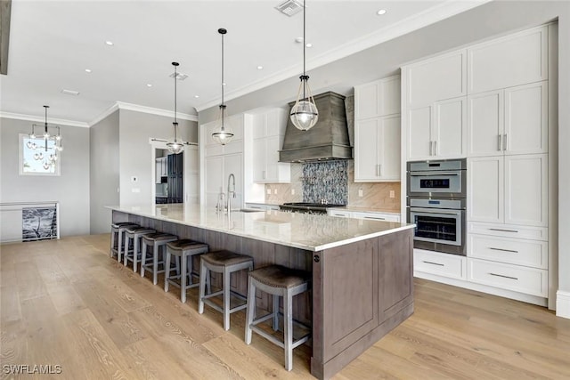 26906 Mclaughlin Blvd, Bonita Springs, FL 34134 - kitchen with custom range hood, crown molding, white cabinetry, light wood-style floors, and backsplash