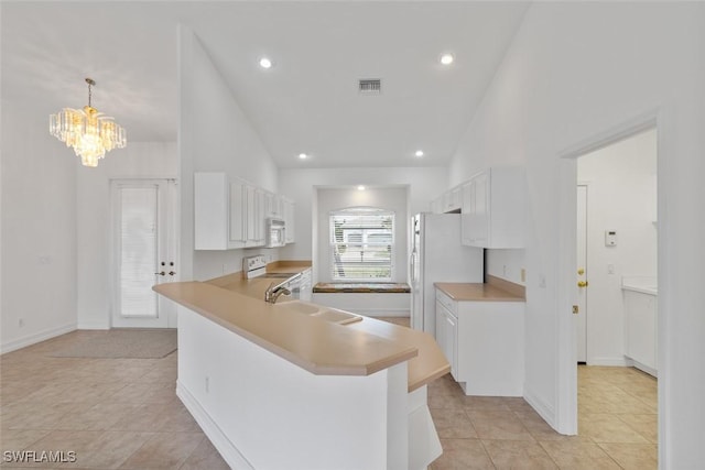 kitchen featuring a sink, white appliances, a chandelier, vaulted ceiling, and white cabinets
