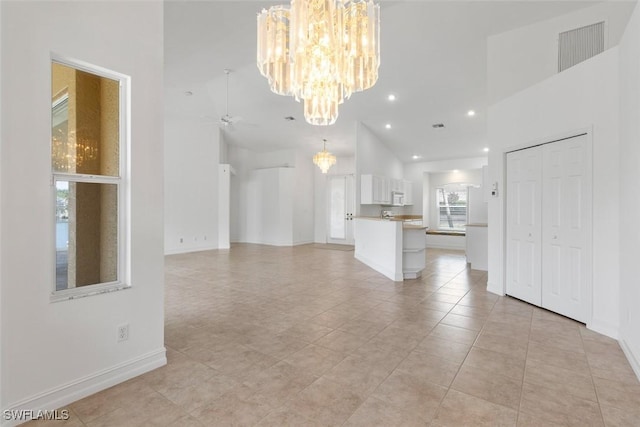 unfurnished living room featuring a chandelier, a high ceiling, ceiling fan, baseboards, and recessed lighting