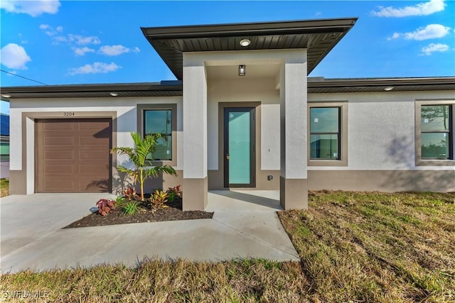 view of exterior entry featuring stucco siding, a garage, and concrete driveway