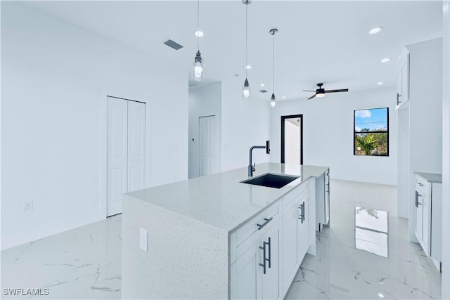 kitchen featuring a sink, light marble finish floors, white cabinets, and recessed lighting