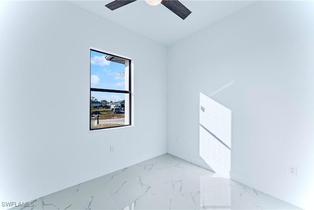 spare room featuring marble finish floors, baseboards, and a ceiling fan