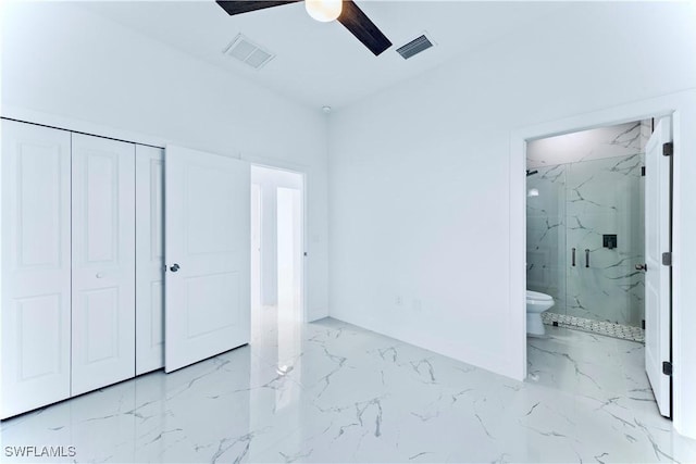 unfurnished bedroom featuring marble finish floors, a closet, ensuite bathroom, and a ceiling fan