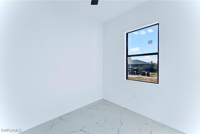 spare room featuring marble look tiles and baseboards