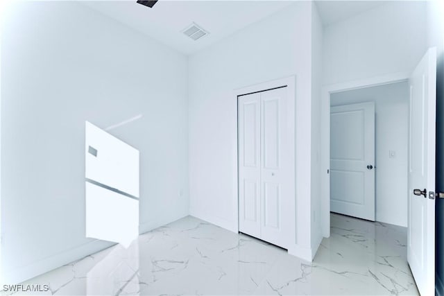 unfurnished bedroom with marble finish flooring, baseboards, and a closet