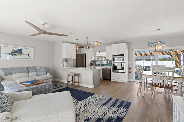 living room featuring a chandelier, baseboards, wood finished floors, and ceiling fan