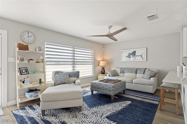 living room with a ceiling fan, light wood-style flooring, and baseboards