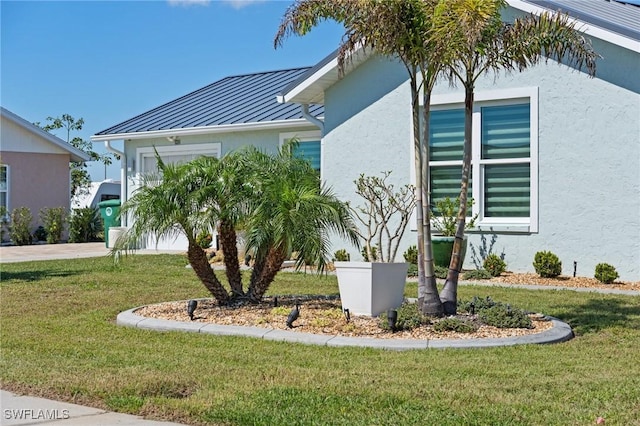 view of side of home featuring a standing seam roof, a yard, stucco siding, and metal roof