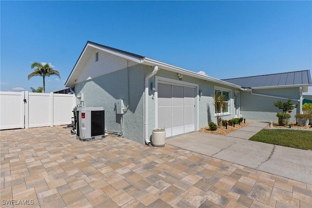 view of home's exterior with an attached garage, a gate, driveway, stucco siding, and fence