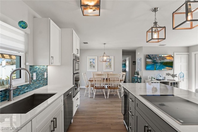 kitchen featuring a sink, appliances with stainless steel finishes, backsplash, dark wood-style flooring, and light countertops