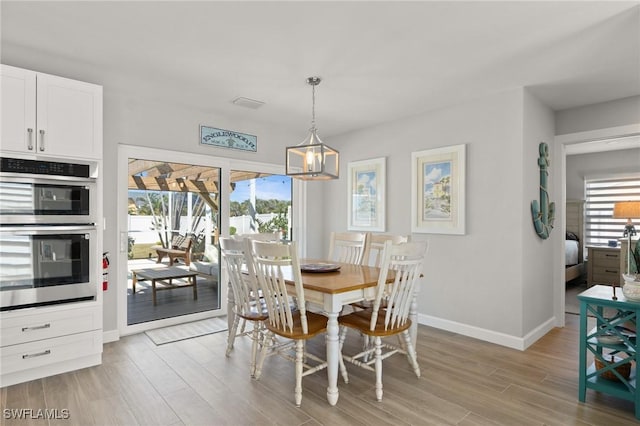dining room featuring light wood-style floors, a chandelier, and baseboards