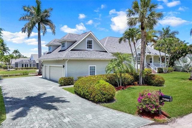 27150 Mora Rd, Bonita Springs, FL 34135 - view of side of home featuring a shingled roof, decorative driveway, a lawn, a garage, and a porch