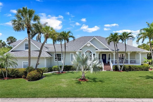 27150 Mora Rd, Bonita Springs, FL 34135 - view of front of home with a porch, a front yard, board and batten siding, and a chimney