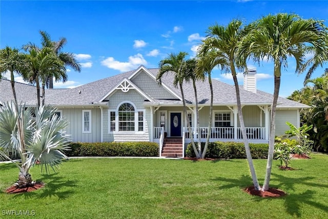 27150 Mora Rd, Bonita Springs, FL 34135 - view of front of home with a chimney, a porch, a front lawn, board and batten siding, and roof with shingles