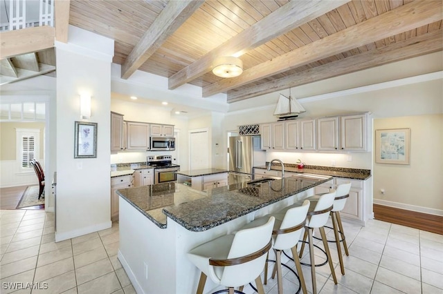 27150 Mora Rd, Bonita Springs, FL 34135 - kitchen featuring appliances with stainless steel finishes, light tile patterned floors, a large island with sink, a sink, and wooden ceiling with exposed beams