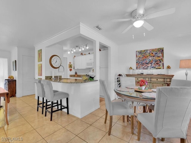 kitchen featuring dark stone counters, light tile patterned floors, ceiling fan, white cabinetry, and white microwave