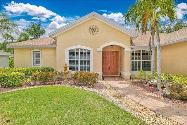 7810 Twin Eagle Ln, Fort Myers, FL 33912 - view of front of house with a front yard, a shingled roof, and stucco siding