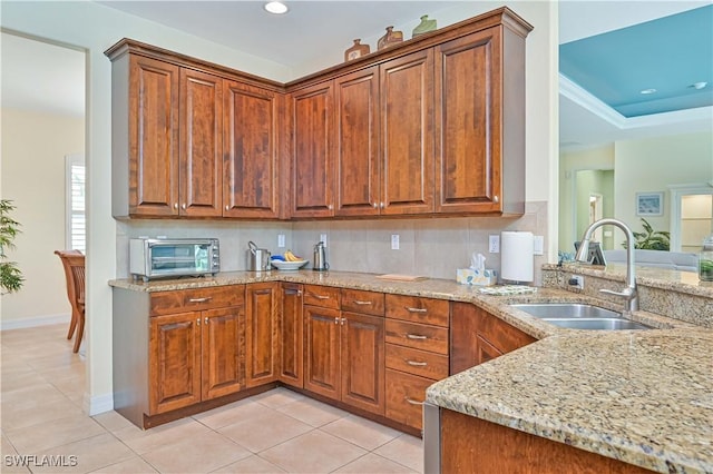 7810 Twin Eagle Ln, Fort Myers, FL 33912 - kitchen featuring a sink, light stone counters, light tile patterned floors, brown cabinets, and recessed lighting