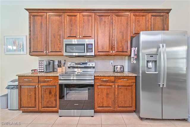 7810 Twin Eagle Ln, Fort Myers, FL 33912 - kitchen with appliances with stainless steel finishes, brown cabinetry, light stone counters, and light tile patterned floors