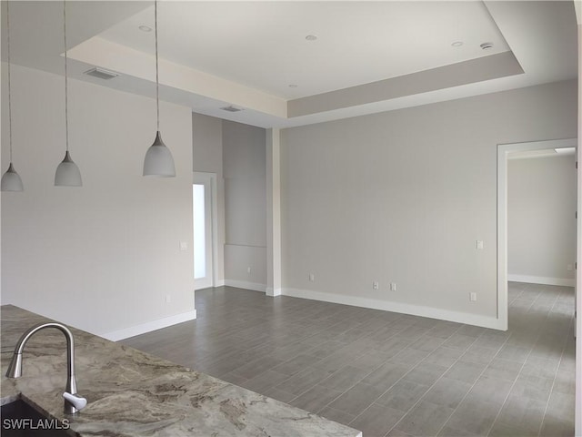 3607 SW 8th Ct, Cape Coral, FL 33914 - unfurnished living room featuring a tray ceiling, dark wood-style flooring, and baseboards