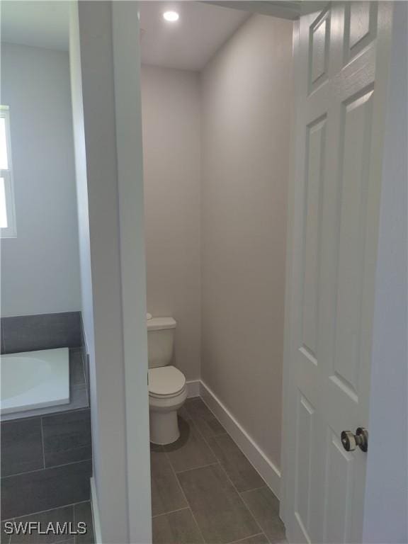 3607 SW 8th Ct, Cape Coral, FL 33914 - bathroom featuring toilet, a relaxing tiled tub, baseboards, recessed lighting, and tile patterned flooring