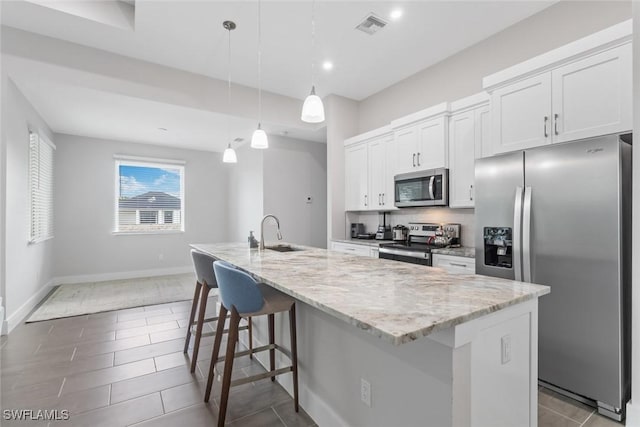 3607 SW 8th Ct, Cape Coral, FL 33914 - kitchen featuring stainless steel appliances, white cabinets, an island with sink, light stone countertops, and a breakfast bar area