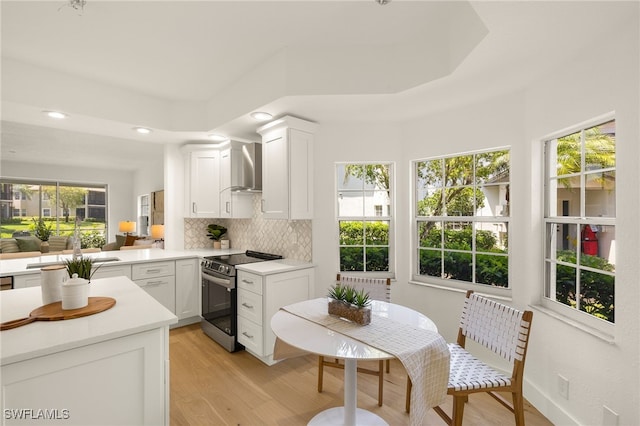 4485 Dover Ct Unit 1202, Naples, FL 34105 - kitchen featuring stainless steel electric range oven, light wood-style flooring, wall chimney range hood, tasteful backsplash, and recessed lighting