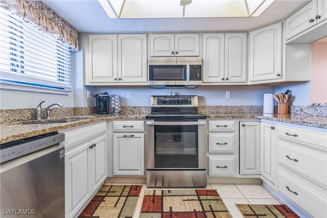 226 3rd St Unit 208, Bonita Springs, FL 34134 - kitchen featuring appliances with stainless steel finishes, a sink, white cabinets, and light stone counters