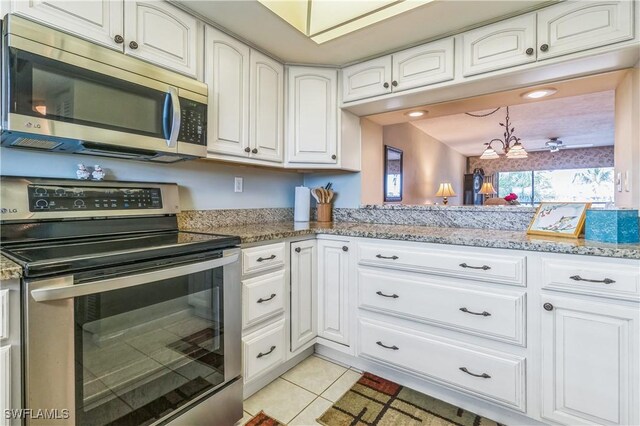 226 3rd St Unit 208, Bonita Springs, FL 34134 - kitchen featuring appliances with stainless steel finishes, white cabinetry, light tile patterned floors, and light stone counters