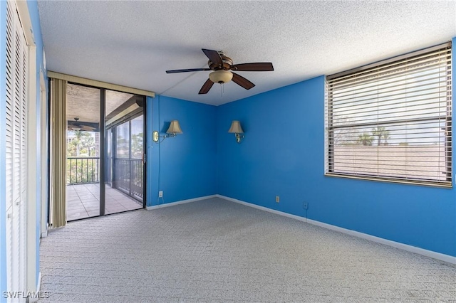 3460 N Key Dr Unit 210, North Fort Myers, FL 33903 - empty room with carpet flooring, a ceiling fan, a textured ceiling, expansive windows, and baseboards