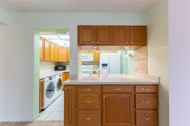3460 N Key Dr Unit 210, North Fort Myers, FL 33903 - kitchen with white appliances, separate washer and dryer, light countertops, brown cabinetry, and decorative backsplash