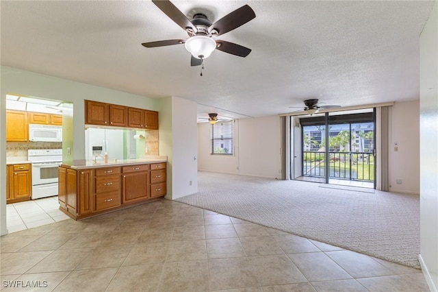 3460 N Key Dr Unit 210, North Fort Myers, FL 33903 - kitchen with white appliances, a ceiling fan, light colored carpet, open floor plan, and a textured ceiling